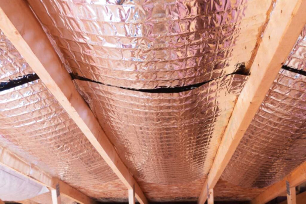 Insulation of attic with fiberglass cold barrier and reflective heat barrier