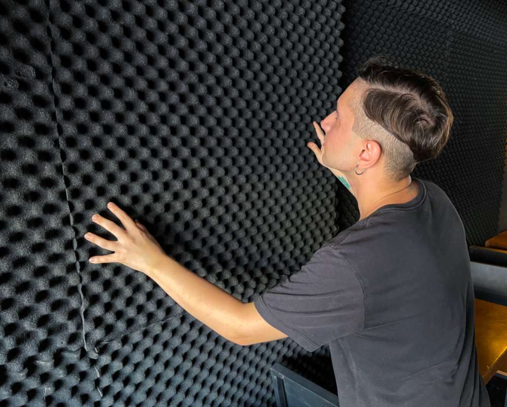 Person installing black acoustic foam panels for soundproof insulation